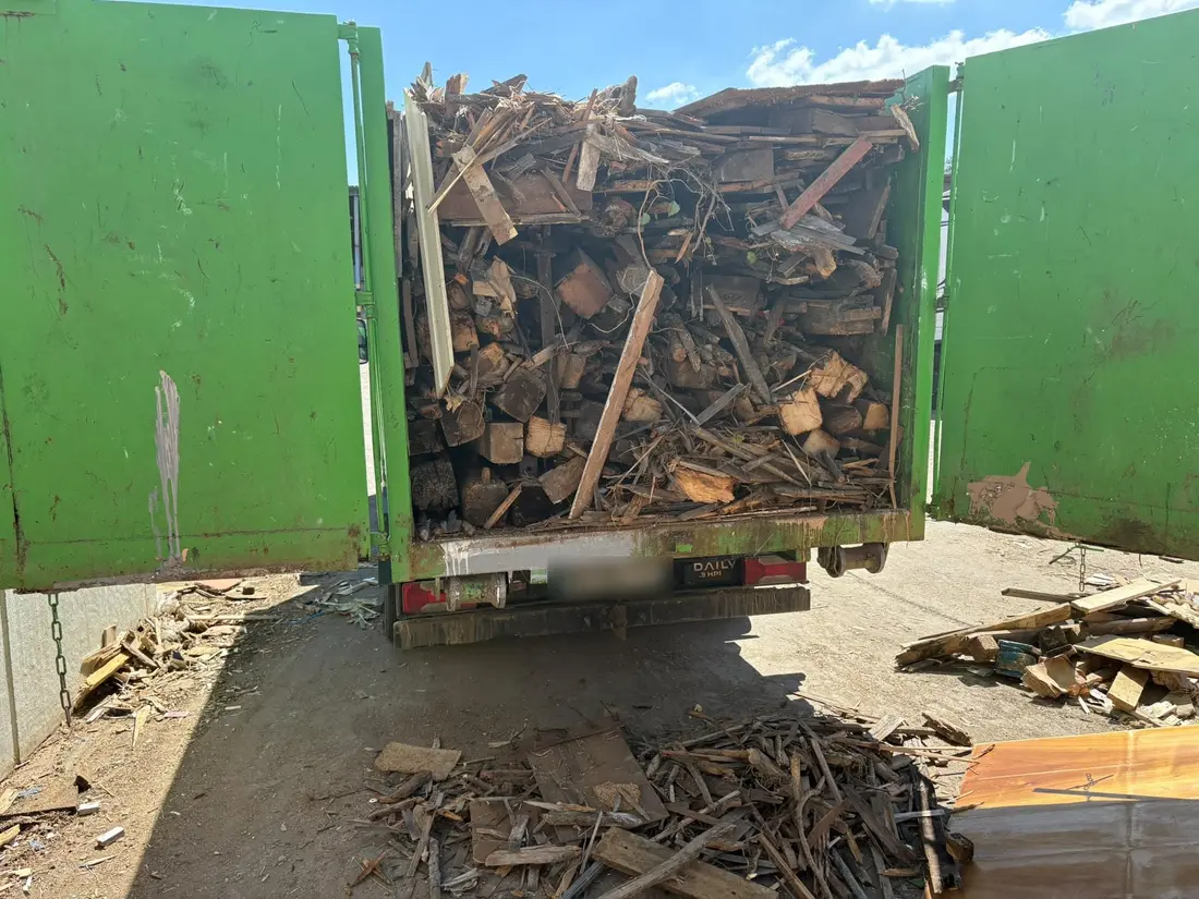 Benne verte chargée de bois de démolition sur un camion, portes arrière ouvertes