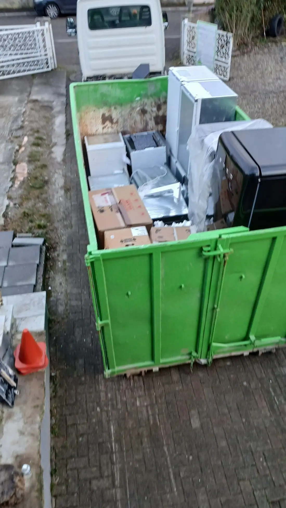 Benne chargée d'électroménager, de cartons et de mobilier devant un utilitaire