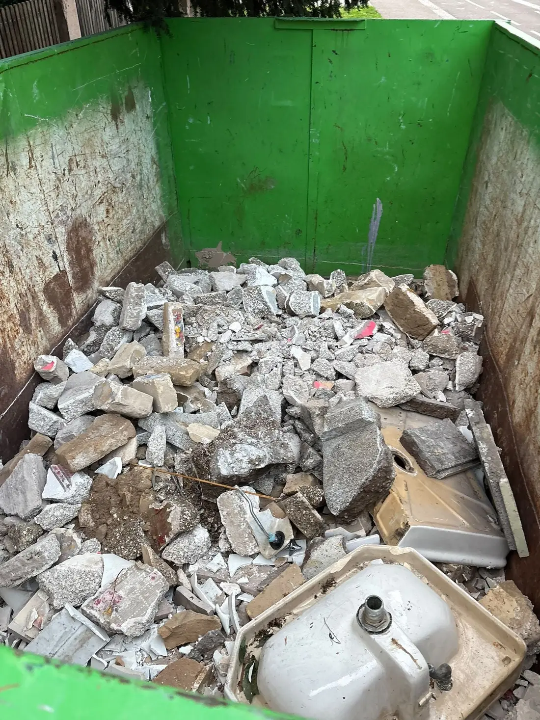 Intérieur de benne rempli de gravats de béton et de morceaux de carrelage